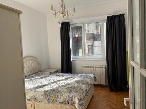- une chambre avec un lit et une fenêtre avec des rideaux noirs dans l'établissement Apartment August 11, à Sofia