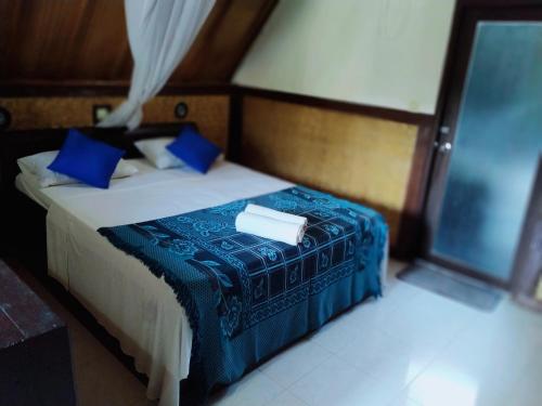 1 dormitorio con 1 cama con sábanas azules y almohadas azules en DEA Gili Cottages, en Gili Meno