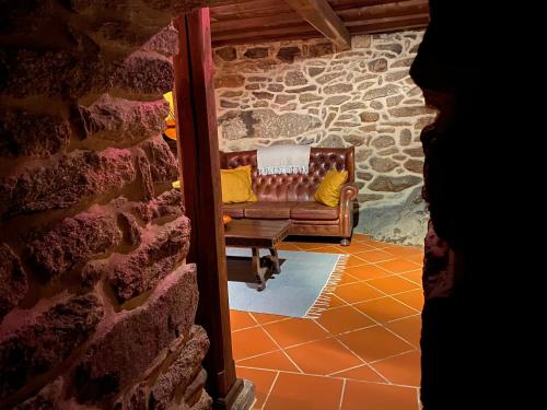 a couch sitting in a room with a stone wall at Casa Garcia - Chaves in Chaves