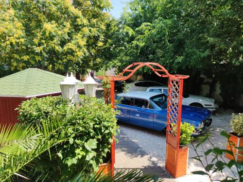 a blue car parked in a driveway with an orange gate at Hotel Oswaldo in Budapest