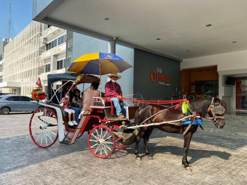 a horse pulling a carriage with a group of people at The Space Hotel Lampang in Lampang