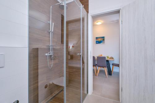 a glass shower in a bathroom with a table at House Torre Apartments in Mali Lošinj
