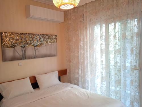 a bedroom with a white bed and a window at Central Home Kavala "private parking" in Kavala