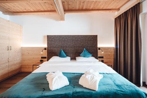 a bedroom with a bed with two towels on it at Hotel Plan de Gralba - das Berghotel in Selva di Val Gardena