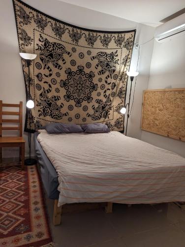 a bedroom with a bed with a black and white headboard at אשראם בכרמל - המקום של אורי in Dāliyat el Karmil