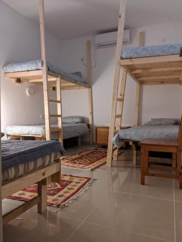 a room with three bunk beds and a table at אשראם בכרמל - המקום של אורי in Dāliyat el Karmil