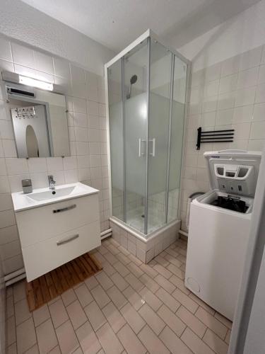 une salle de bain blanche avec une douche et un lavabo dans l'établissement Grand T2 proche de la mer, à Sète