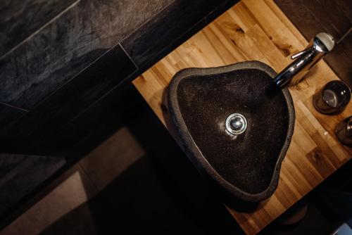 a bathroom with a black sink on a wooden floor at Szumilove Domki z saunami w Bieszczadach in Baligród