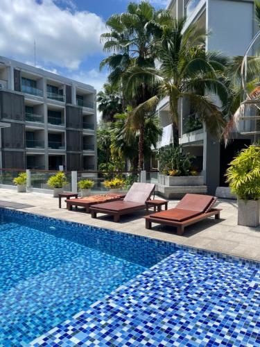 a swimming pool with chaise lounges next to a building at The Regent Bangtao Apartments in Bang Tao Beach