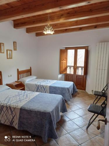 3 camas en una habitación con techos de madera en Casa Borro, en Salvatierra de Esca