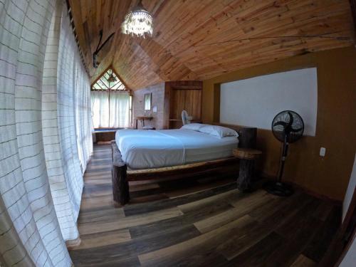 1 dormitorio con cama y techo de madera en EcoHostal Rio Piedra en El Zaino