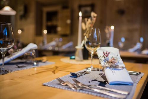 una mesa con copas de vino y cubiertos en Hotel Alp Cron Moarhof en Valdaora