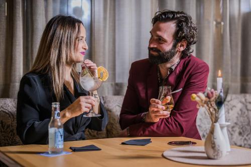 a man and woman sitting at a table with drinks at Moar's Hotel in Valdaora