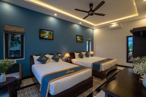 a bedroom with two beds and a ceiling fan at Coco Island Villa in Hoi An