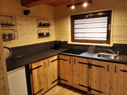 a kitchen with wooden cabinets and a sink and a window at Reset Bieszczady in Bystre