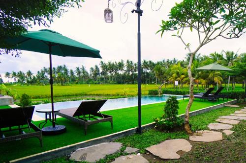 a pool with chairs and an umbrella and a table at Adil Villa & Resort in Ubud