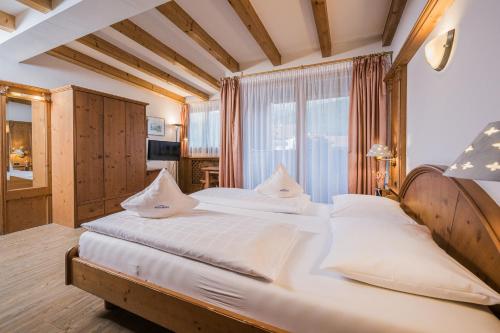 a bedroom with a large bed with white sheets at Hotel Alp Cron Moarhof in Valdaora