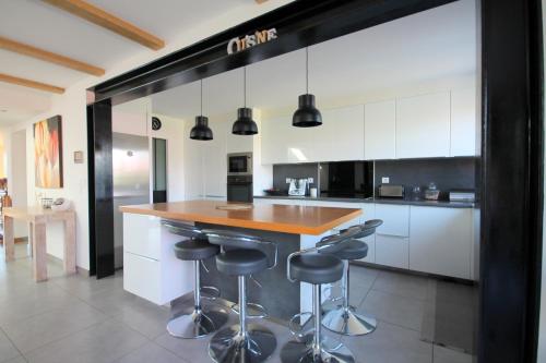 a kitchen with white cabinets and a counter with bar stools at Grande Chambre meublé chez l'habitant in Coignières