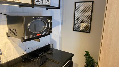 a television hanging on a wall in a kitchen at Novo Studio Garden in Sao Paulo