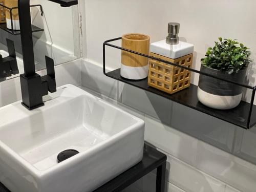 a bathroom with a white sink and a black shelf at Novo Studio Garden in Sao Paulo
