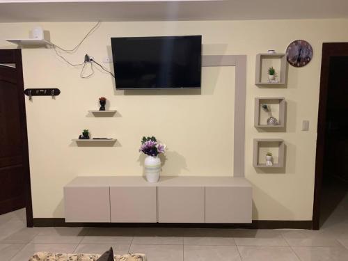 sala de estar con TV en una pared blanca en Hermoso departamento cerca de todo, en Guayaquil