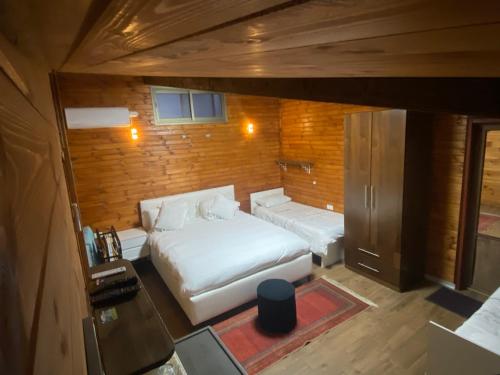 1 dormitorio con 2 camas blancas y pared de madera en Majdal Shams/989 Apartment, en Nimrod