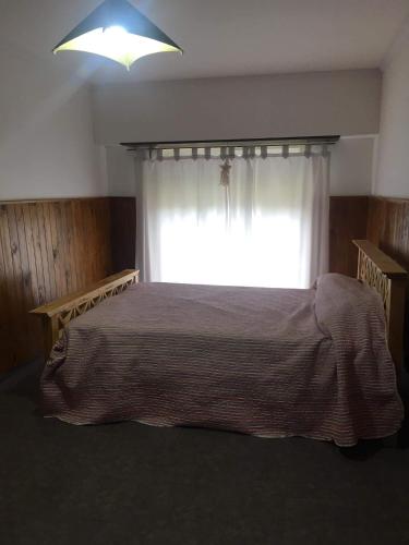 Schlafzimmer mit einem Bett vor einem Fenster in der Unterkunft Casa por día in Olavarría