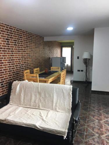 ein Wohnzimmer mit einem Tisch und einer Ziegelwand in der Unterkunft Casa por día in Olavarría