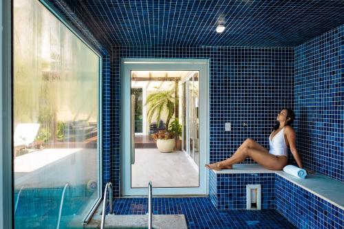 una mujer sentada en una bañera en un baño de azulejos azules en Pousada Apple House Paraty, en Paraty