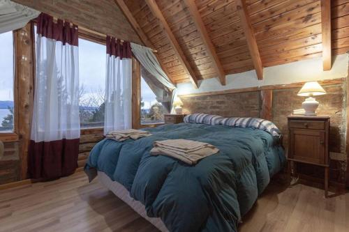 1 dormitorio con 1 cama grande en una cabaña de madera en Casa con vista al lago - La casa de Berta en San Carlos de Bariloche