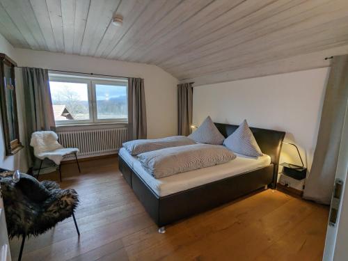 um quarto com uma cama, uma cadeira e uma janela em Ferienwohnung Murnauer Moos em Murnau am Staffelsee