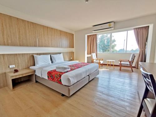 Sea Paradise Hotel Sattahip في ساتاهيب: غرفة فندقية بسرير وطاولة وكراسي