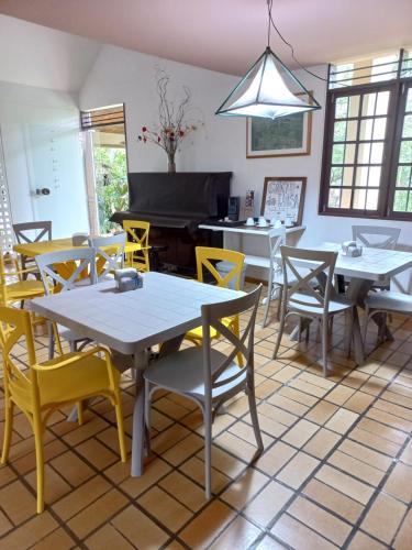 a dining room with tables and chairs and a piano at HOSTEL Recanto do Cajueiro in Maceió