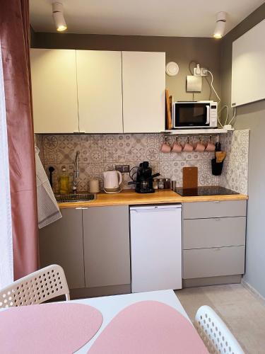 a small kitchen with white cabinets and a pink table at Apartamenty Jagodzianka - Jacuzzi, Sauna, Tężnia solankowa in Ustrzyki Dolne