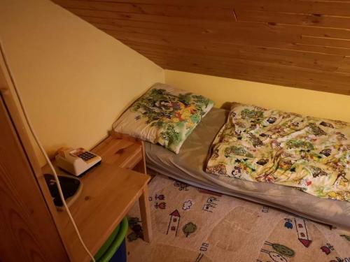 2 Betten in einem kleinen Zimmer mit einem Tisch in der Unterkunft M&M Chata Kokava Línia in Å oltÃ½ska