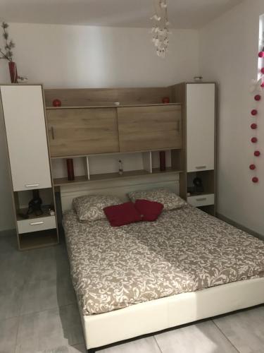 uma cama com duas almofadas vermelhas num quarto em Appartement confortable centre du village em Pélussin