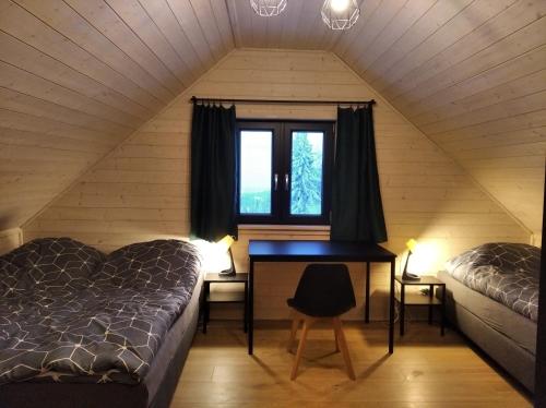 dwa łóżka i biurko w pokoju z oknem w obiekcie Sowi Stok w mieście Sokolec