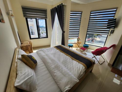 a bedroom with a large bed with two chairs and windows at K Bình Phương Hotel in Da Lat