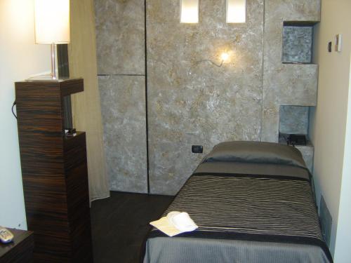 a bedroom with a bed and a stone wall at Casa alle Colonne by Hotel Ancora in Verbania
