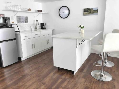 een keuken met witte kasten en een tafel en een klok bij Romantic Studio Cottage in Lambton Shores