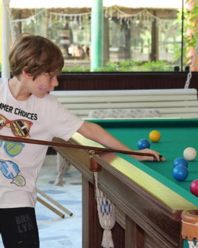 a young boy playing pool at a pool table at Hotel Fazenda Bonanza in Engenheiro Paulo de Frontin