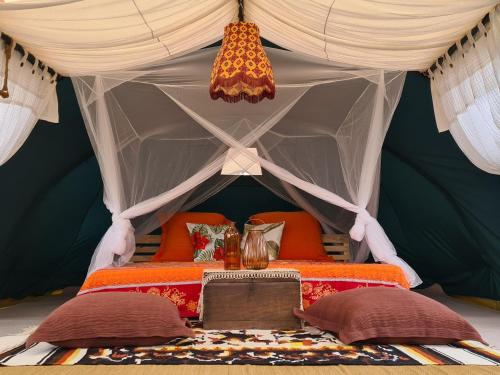 a bed in a tent with pillows and a table at Villa Noina Glamping in Ban Nong Takhain