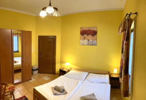 a bedroom with a bed and a yellow wall at Villa Victoria Penzion in Liptovský Ján