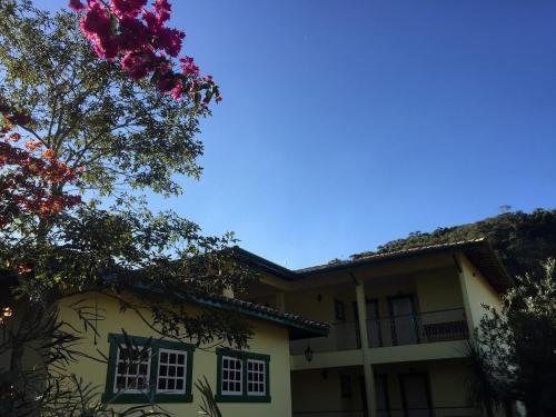 a house with a flowering tree in front of it at Pousada Primavera in São Luiz do Paraitinga