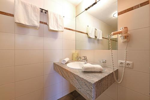 ein Bad mit einem Waschbecken und einem Spiegel in der Unterkunft Tre Soli Appartements Restaurant in Schoppernau