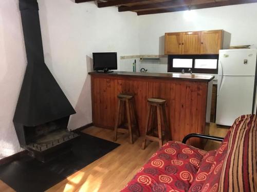 a kitchen with a fireplace and a counter with stools at Casa ideal para pareja en Bella Vista - Maldonado in Bella Vista