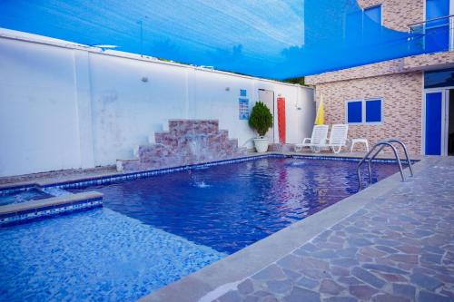 una piscina con 2 sillas y un edificio en Cabanas Villa Antonella Covenas, en Coveñas