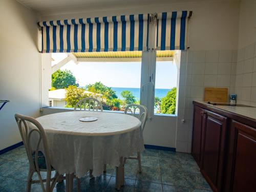 a kitchen with a table and chairs and a large window at Résidence Madicréoles in Le Carbet