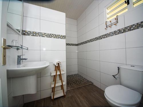 La salle de bains blanche est pourvue de toilettes et d'un lavabo. dans l'établissement Résidence Madicréoles, à Le Carbet