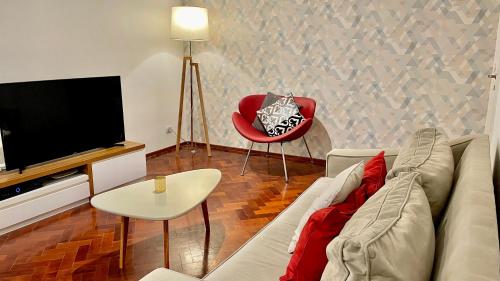 a living room with a couch and a tv and a red chair at Mdz Apartments in Mendoza